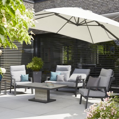 Eine Terrasse mit Gartenmöbeln und großem Ampelschirm